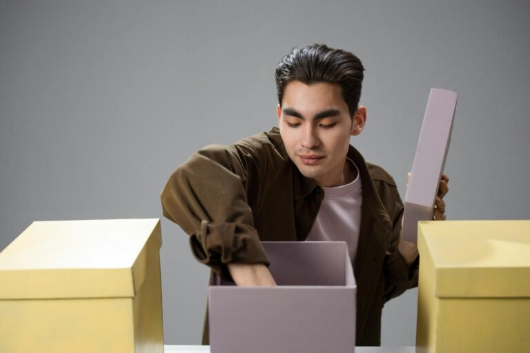 A young Asian man explores contents inside boxes, creating curiosity and engagement.